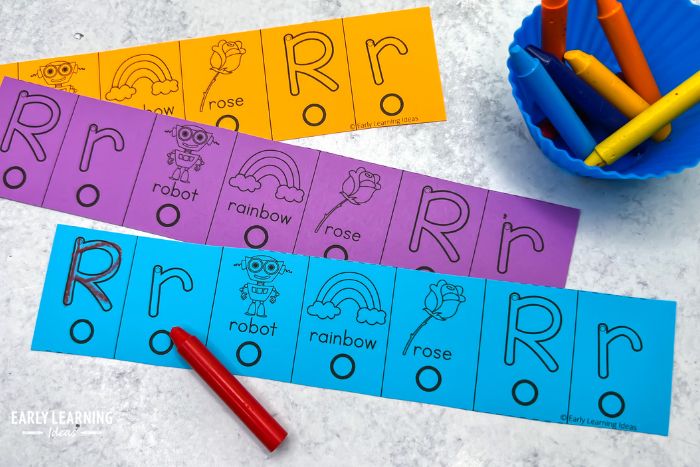 hole punch printable alphabet activity.  The images shows a letter r hole punch letter activity in aqua, purple, and orange, along with some brightly colored crayons.