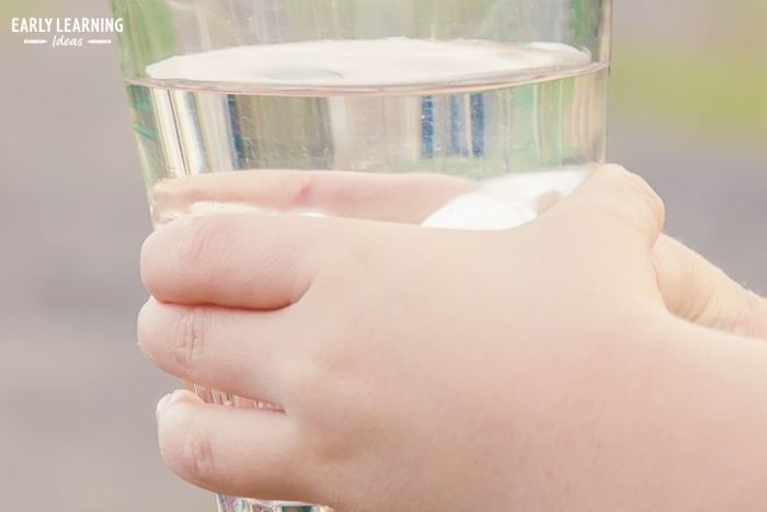 child holing a glass of water and getting ready to do an experiment