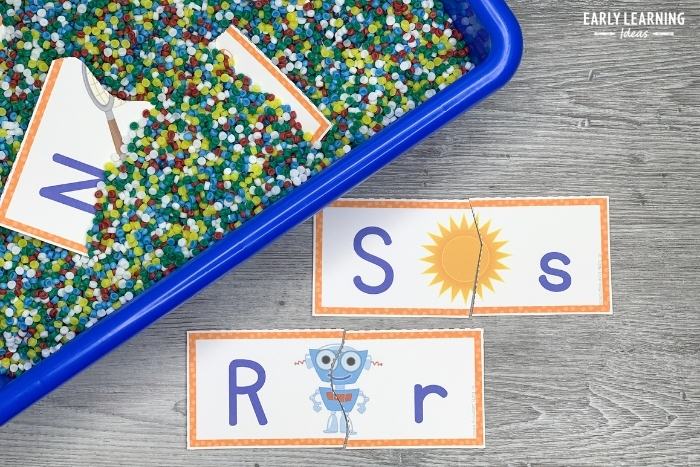 alphabet puzzle for preschoolers in a sensory bin filled with plastic bits