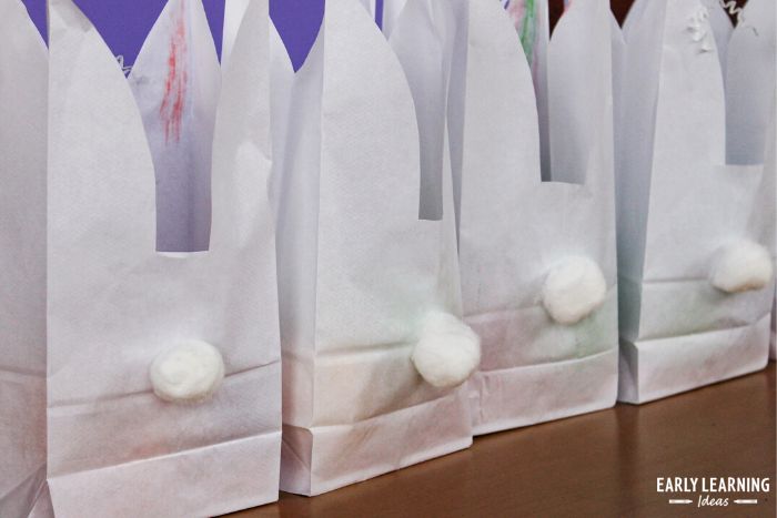 paper bag Easter bunny craft for preschoolers with cotton ball tails on the back of the bag
