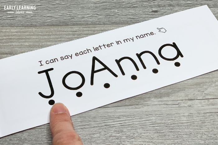 On this personalized name book page, there is a dot under each letter of the name Joanna.  A finger is touching the dot under the first letter of the name.