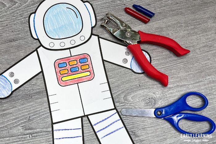 printable astronaut craft and fine motor activity.  The printable craft is shown with a hole punch and scissors and is an example of easy space themed crafts for kids.
