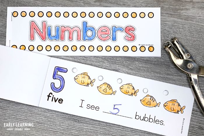 Printable hole punch number books for preschoolers.  The picture shows two books with a silver hole puncher.  One book is open to the number 5 page.  It says "I see 5 bubbles" and each bubble above 5 fish is punched out with a hole punch.
