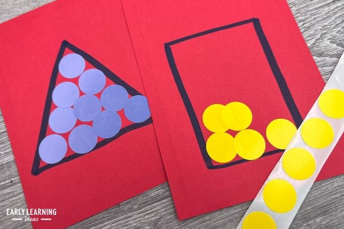 A triangle and rectangle are drawn on pieces of red paper.  A child is filling the inside of the shapes with yellow and blue dot stickers.