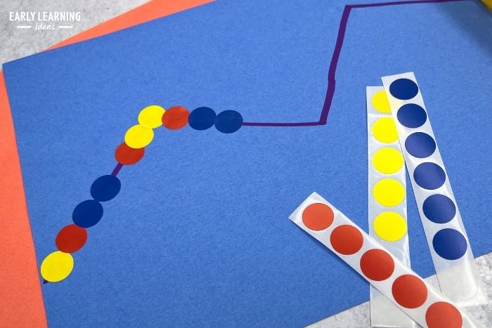 an example of dot sticker activities - A piece of construction paper with a zig-zag line on it.  Kids are placing red, yellow, and blue dot stickers on the line.