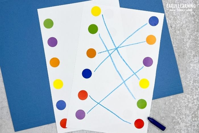 rows of dot stickers on a half-sheet of white paper.  A child has drawn a line with a crayon to connect the dots - an example of a dot sticker activity for fine motor skills.