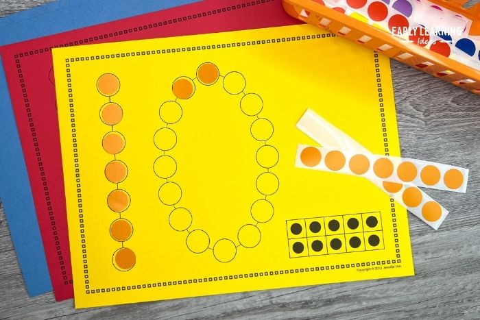 A dot sticker printable with the number 10 printed on bright yellow paper with some orange stickers. An example of peeling dot sticker activities to build fine motor skills.