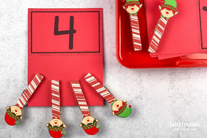 A Christmas clothespin clip math fine motor activity with cute elf clothespin clips on a number 4 counting clip card.