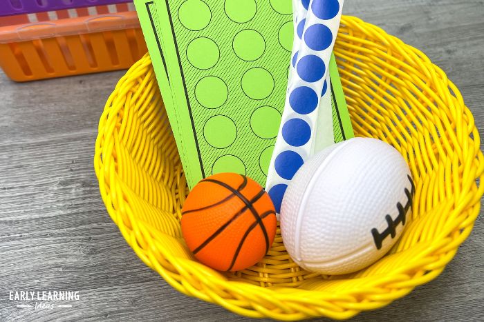 green fine motor task cards shown in a basket with dot stickers and a small basketball and football.