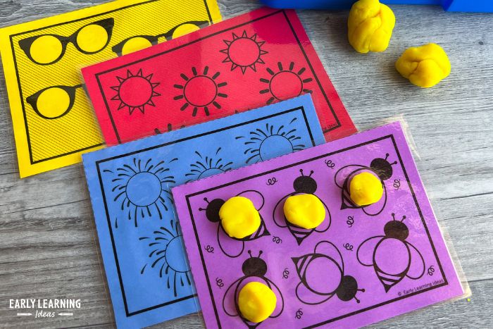 Bee, firework, sun, and sunglasses fine motor task cards used as mini playdough mats and shown with balls of yellow playdough.