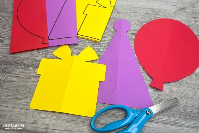 fold and cut activities to help kids build scissor skills.  A gift or present, a birthday hat, and a balloon activity are shown with a pair of scissors.