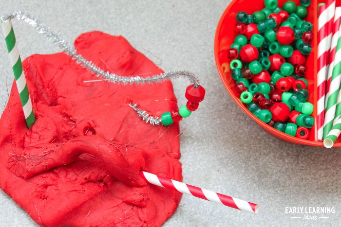 Sparkly Christmas playdough with candy cane straws, pipe cleaner and beads stuck in it.
