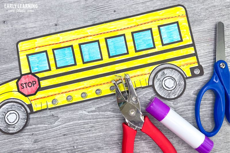 A printable school bus craft.  The cut and paste paper craft is show with scissors, glue stick, and a hole pucnh.