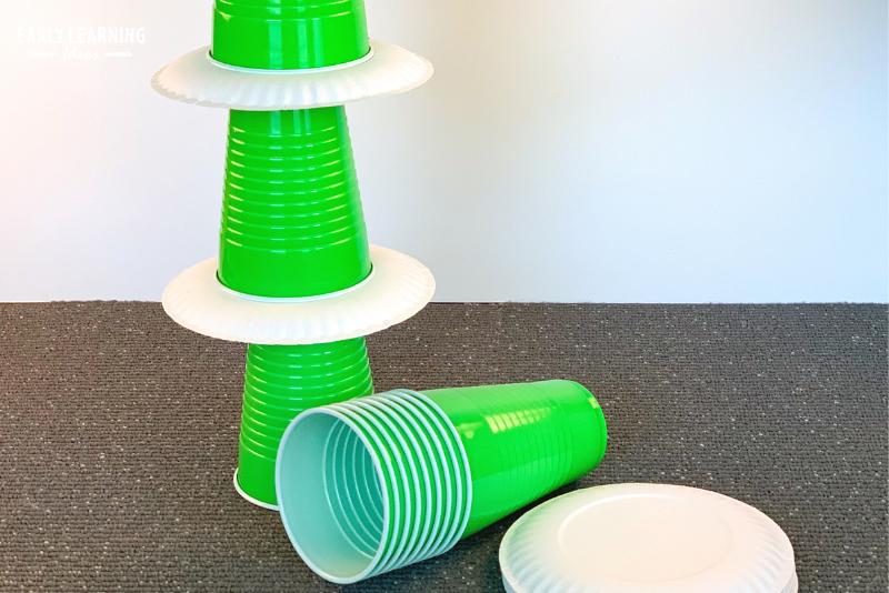 building a tower with green solo cups and paper plates - an example of a fine motor game for preschoolers