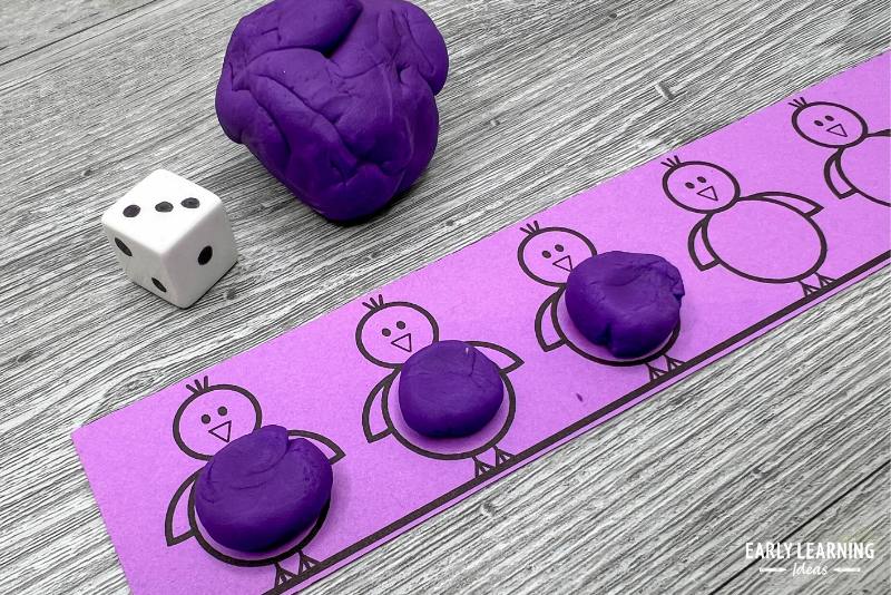 A playdough and dice fine motor game.  A bird game strip is shown with ball of purple playdough on the printable strip.