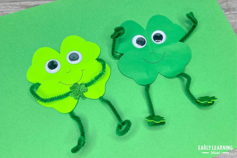 Two shamrock man crafts made from a paper cut out shamrock, pipe cleaners, and googly eyes.  An example of St Patricks Day crafts for preschool kids