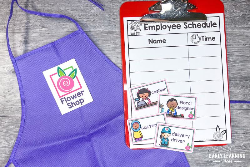 An apron, role name tags, and a schedule for a flower shop dramtic play center.