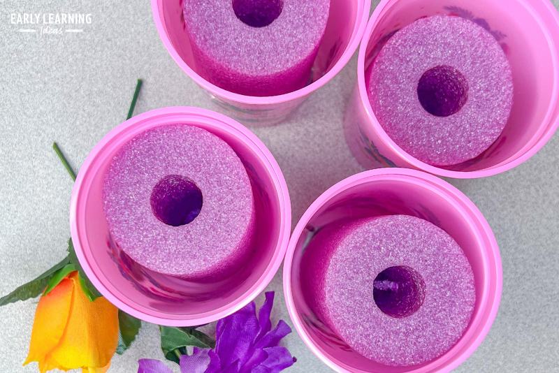 Plastic cups with sections of pool noodles in them ready to use in a flower shop dramatic play area.