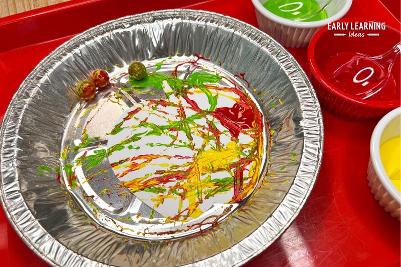 marble printing an apple cutout in a pie pan