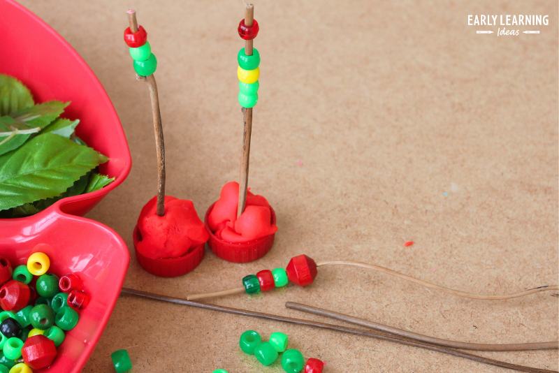 apple playdough tray - balls of red playdough with sticks and red, yellow, and green beads