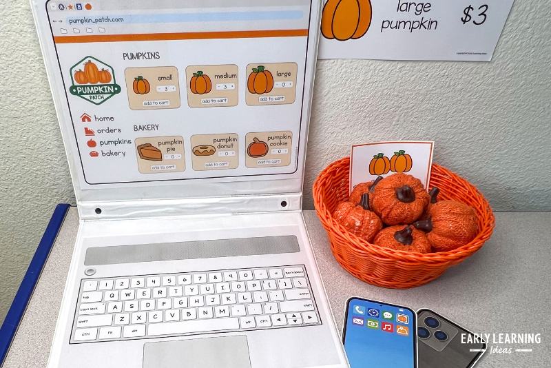 pumpkin patch dramatic play center office shown with a basket of small pumpkins and a printable laptop
