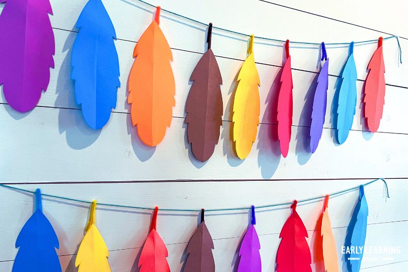 paper feather garland - colorful feathers on a string hung on a white background