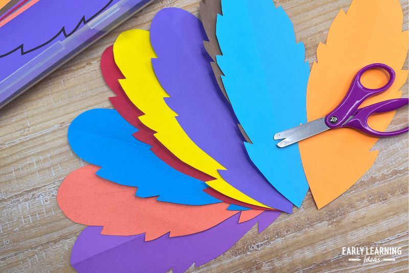 paper feathers in bright colors shown with scissors