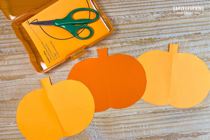 fold and cut pumpkin paper cutting craft shown with scissors
