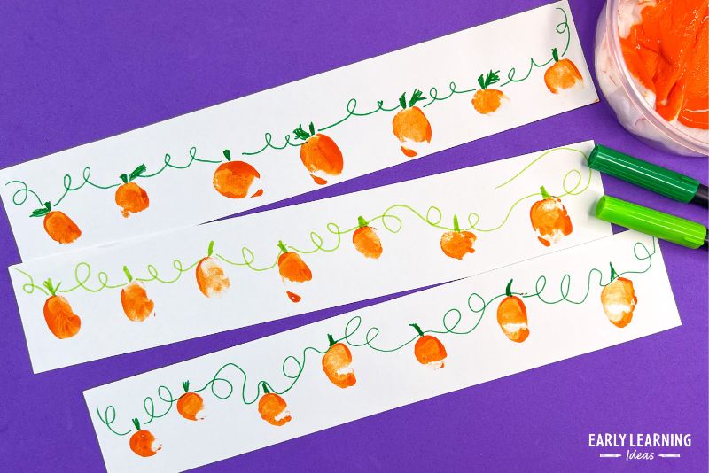 fingerprint pumpkin vines made on white strips of paper and shown with orange paint and green markers