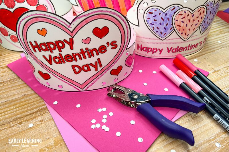 Happy Valentine's Day crowns shown with markers and a hole punch.
