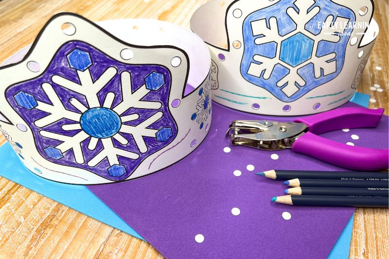 winter snowflake crown headband craft for kids shown with colored pencils and a hole punch