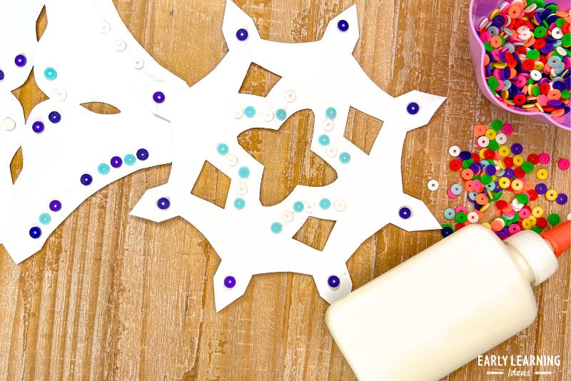winter snow crafts for preschoolers and kindergarteners - a paper snowflake with glue and small disc beads