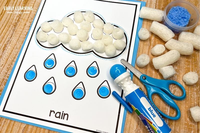 rain cloud craft with a dot marker printable.  Shown with packing peanuts, dot marker, scissors, and crayon
