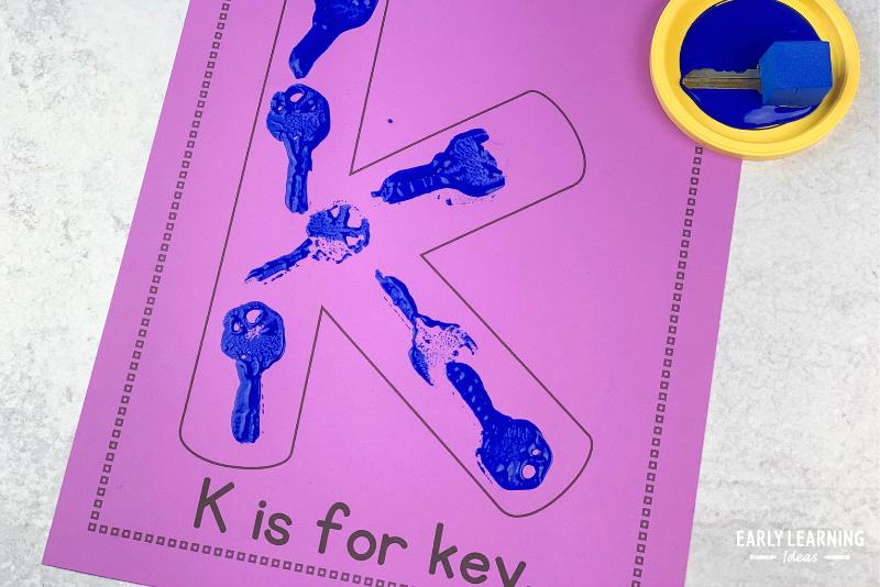 Letter k is for k art project made with a printable alphabet activity page.  A key and paint are used to make key prints on the large bubble letter k printed on the page.