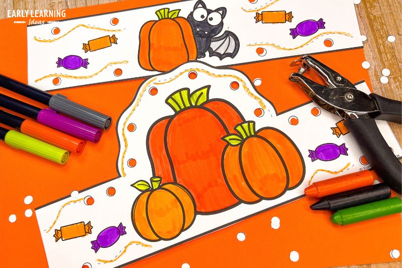 Halloween pumpkin crown craft decorated with hole punches and shown with markers and crayons